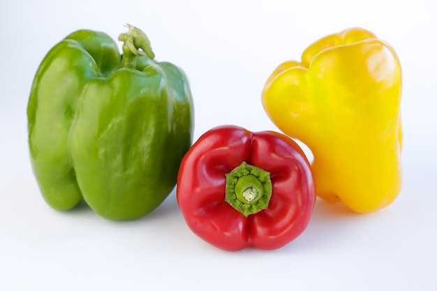 Red green and yellow peppers against white background