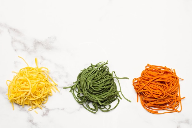 Red green and yellow raw spaghettis on marble kitchen counter