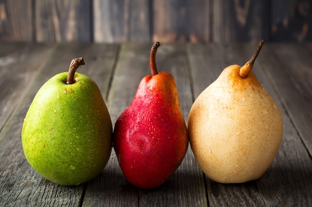 Red, green, yellow sweet pears on a dark