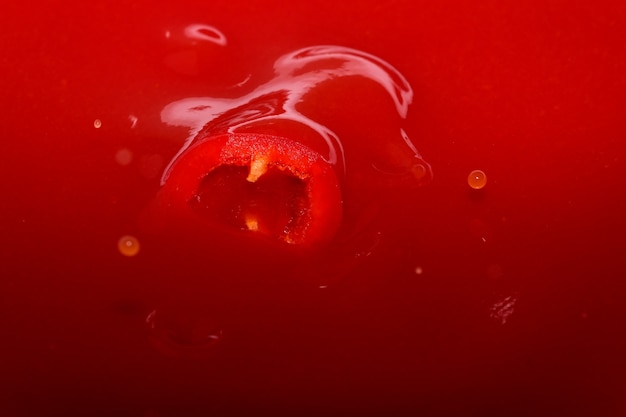 Red grocery background of tomato juice with sweet pepper splash close-up