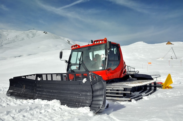 Red groomer parking next to the slopes in a ski resort