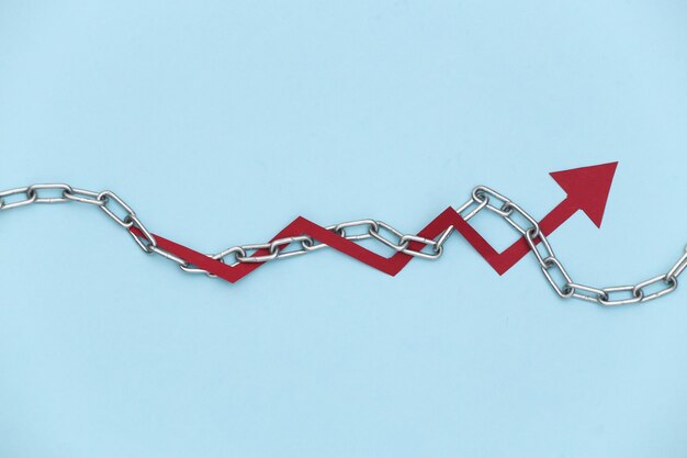 Red growth arrow wrapped in steel chain on blue background