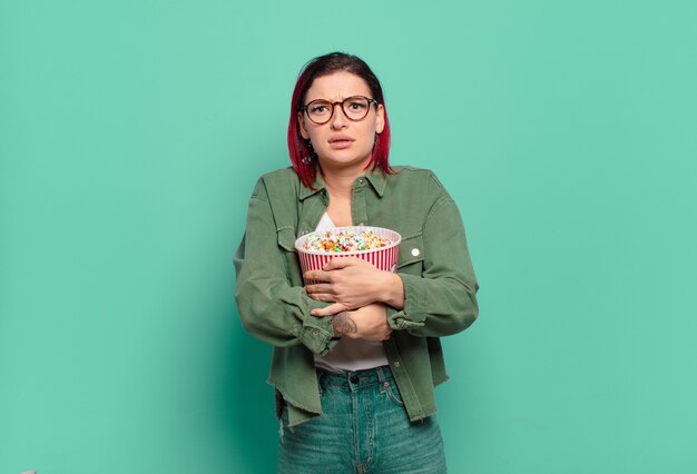 Red hair cool woman with popcorns and a tv remote control