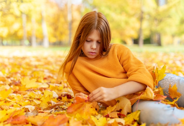 秋の公園で赤い髪の十代の少女