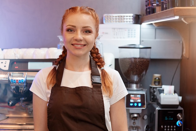 Red haired barista posing in cafe shop