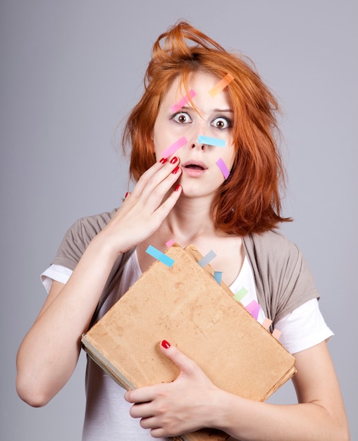 Red-haired businesswoman with book and notes on face.