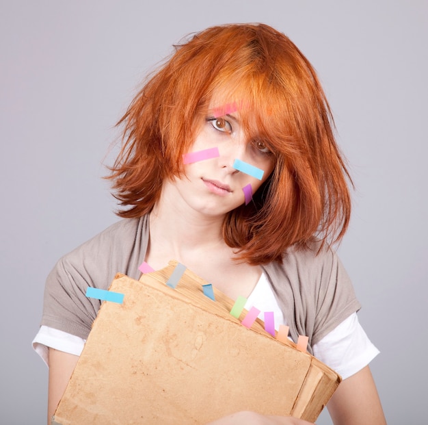 Red-haired businesswoman with book and notes on face.