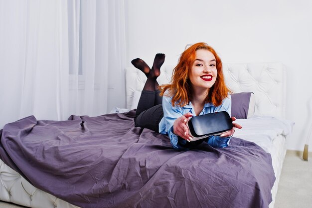 Red haired girl in bed with vr glasses at studio room