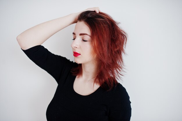 Red haired girl on black dress tunic against white wall at empty room.