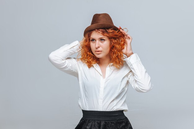 Ragazza dai capelli rossi con cappello marrone e camicia bianca