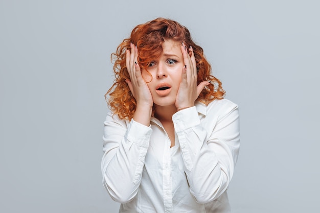 Red-haired girl dissatisfied on a gray background