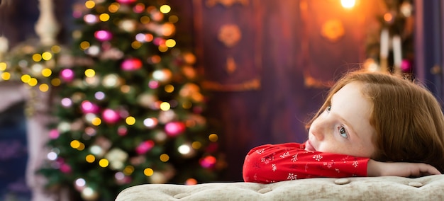 Red-haired girl dreams of near the Christmas tree.