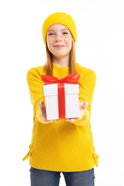 Red-haired girl holds out a box with a gift on a white 