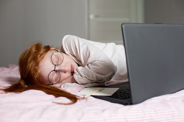 Red-haired girl is home-schooled due to the coronavirus\
pandemic.