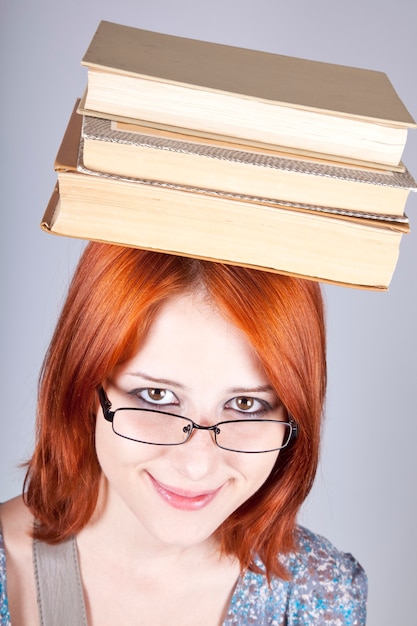 Red-haired girl keep books on her head. 