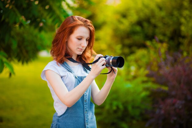 Red-haired girl photographer in the Park