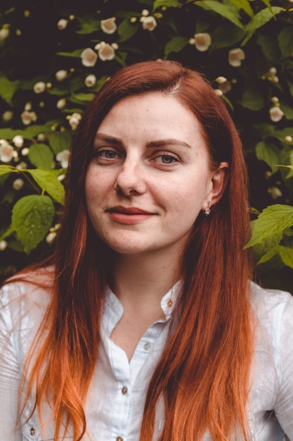 Red haired girl smiling at the camera in the botanical garden