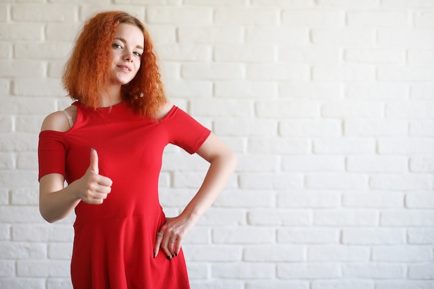 Red-haired girl student on a brick wall background