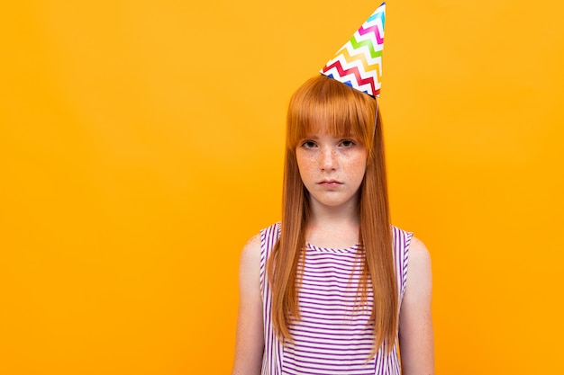 Red-haired girl with a holiday cap  on a yellow