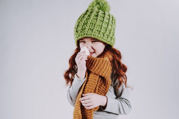 Photo red haired girl with scarf wipes snot with napkin.