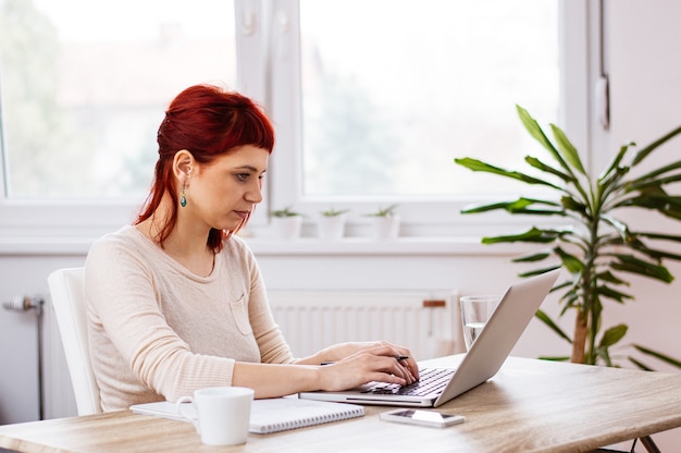 Red haired girl working on a project in an apartment