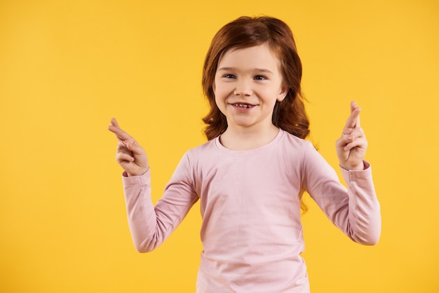 Red haired little girl crossed fingers. Superstition concept