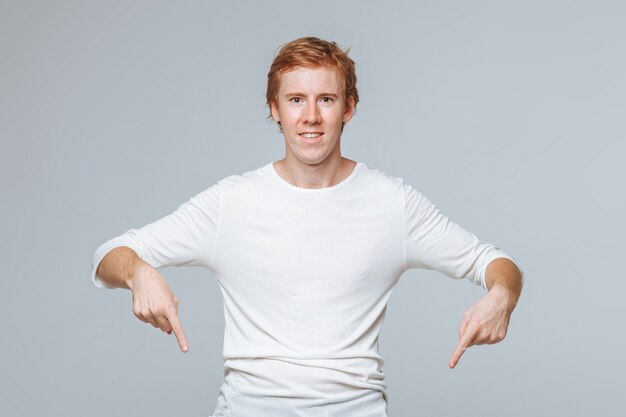 red haired man on a light background points