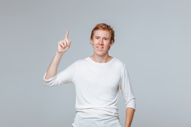 red haired man on a light background points