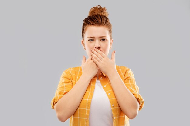 Photo red haired teenage girl covering mouth by hands