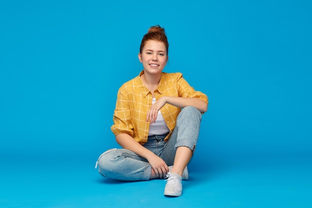 red haired teenage girl in shirt and torn jeans