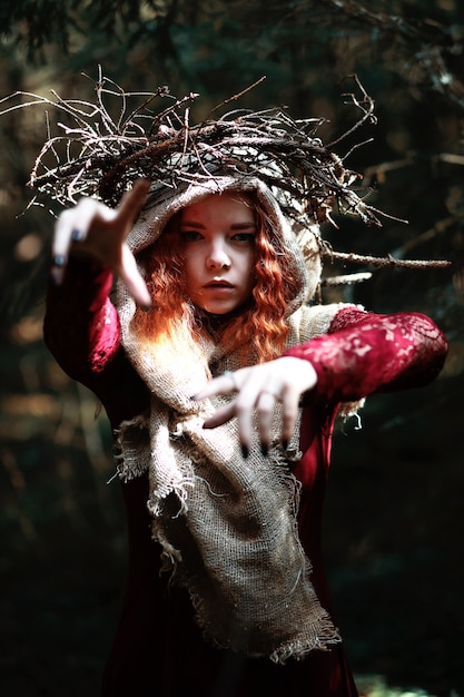 Foto la strega dai capelli rossi tiene un rituale con una sfera di cristallo nella foresta