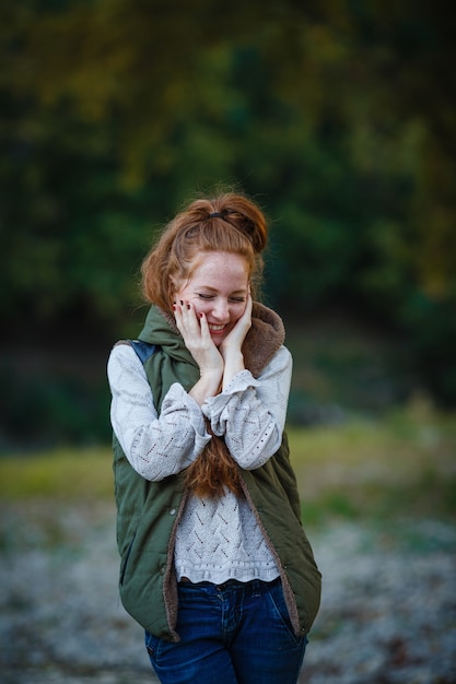 Photo red-haired woman at the beach by the lake in fall clothing