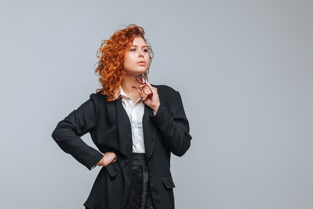 A red-haired woman in a business suit and glasses