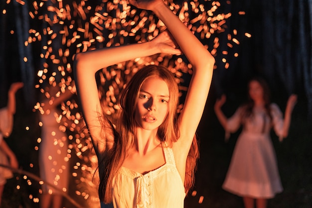 Red-haired woman dancing in front of a fire