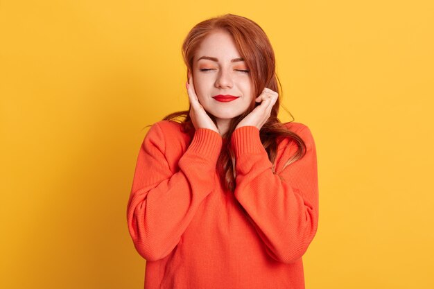 Red haired woman plugging ears with fingers and closing her eyes, not wanting to listen hard loud music