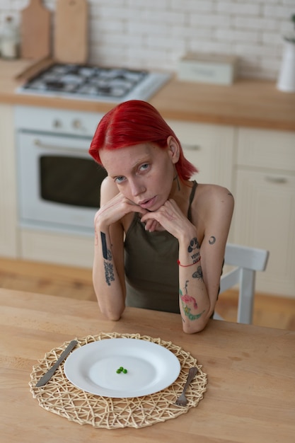 Red-haired woman. Red-haired woman with anorexia sitting in the kitchen feeling bad and hungry