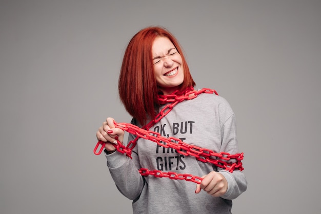 A red-haired woman with brown hair tries to get rid of the chain