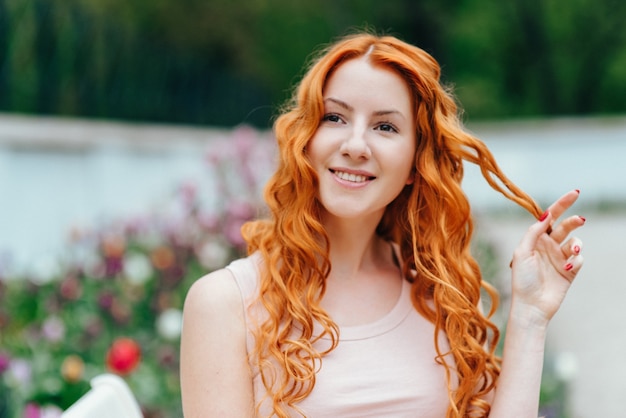 Red-haired young woman walking in a park with big white mansion