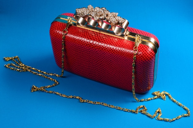 Red handbag clutch with chain on blue
