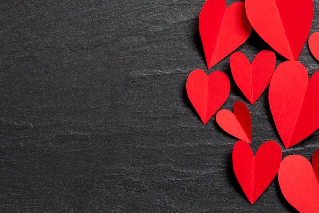 Red handmade paper hearts on a slate background