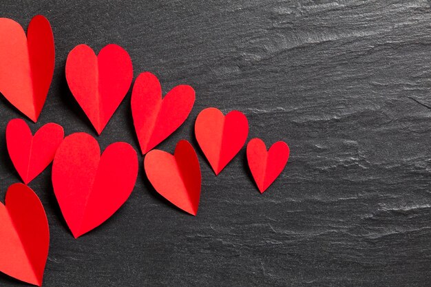 Red handmade paper hearts on a slate background