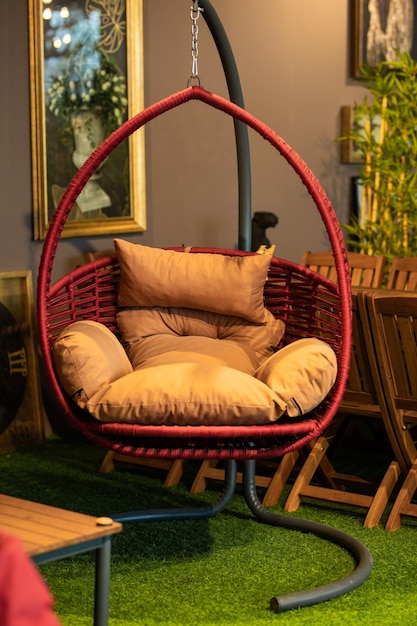 A red hanging chair with a pillow on it