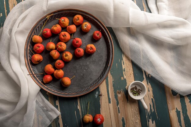 Photo red hawthorn on a plate or scattered on a wooden table