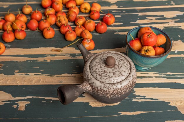 The red hawthorn in the plate and the teapot are on the wooden table