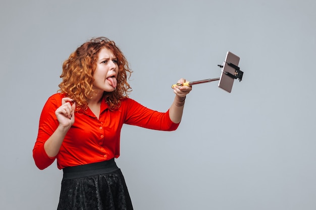 Photo red head girl taking selfie on phone on monopod