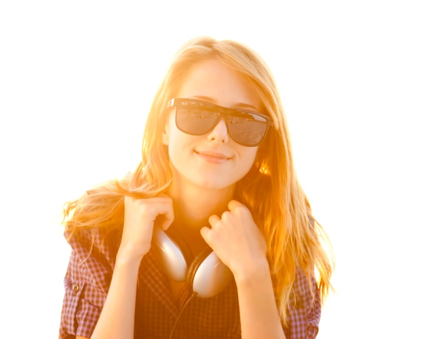 Red-head girl with headphones at the beach in sunrise.