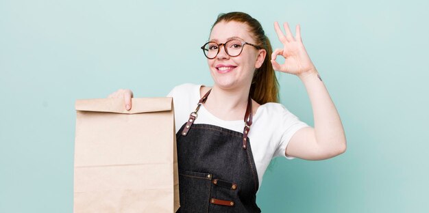 Red head pretty woman feeling happy showing approval with okay gesture take away delivery concept