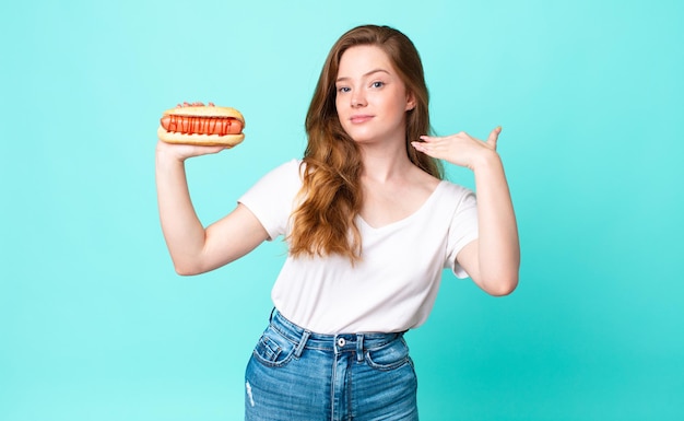 Red head pretty woman feeling stressed, anxious, tired and frustrated and holding a hot dog