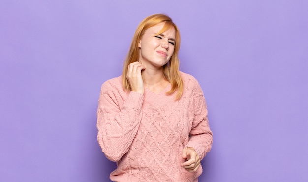 Red head pretty woman feeling stressed, frustrated and tired, rubbing painful neck, with a worried, troubled look