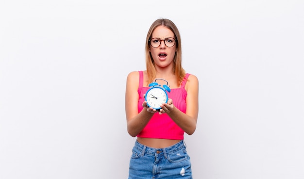 Red head pretty woman holding an alarm clock and expressing a concept